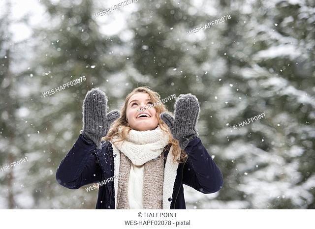 Portrait of happy young woman at snowfall in nature