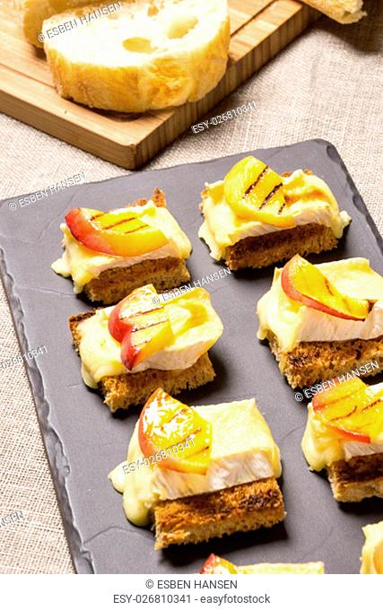 canapes, appetizer with grilled brie and nectarine plated on a slate dish