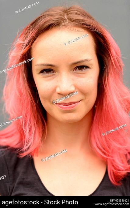 Portrait of beautiful woman with pink hair against gray wall outdoors