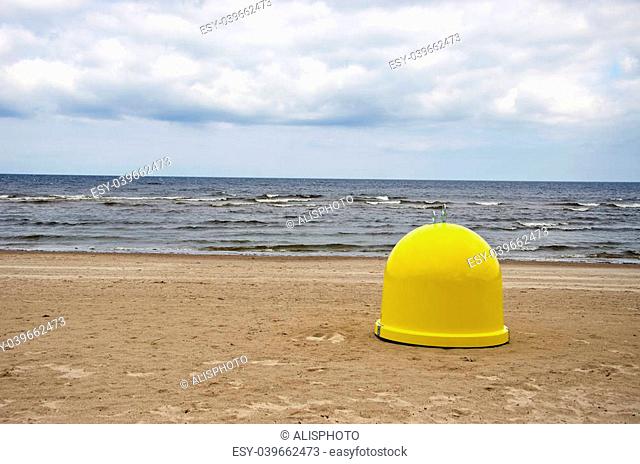 yellow plastic garbage box on beach sand and sea