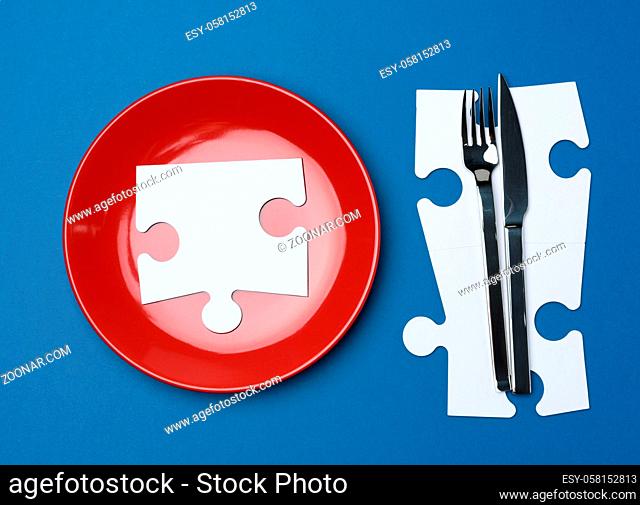 red round ceramic plates, fork with knife on a blue background, top view. Table setting