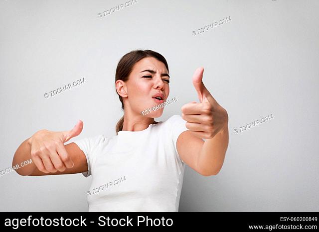 Portrait of happy and smiling young woman with thumbs up. Isolated on white background. High quality photo