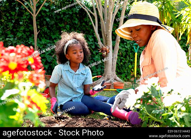 African American girl and her grandmother planting flowers at their garden