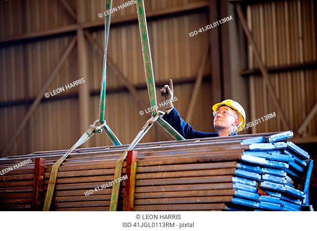 Worker signaling crane at shipyard