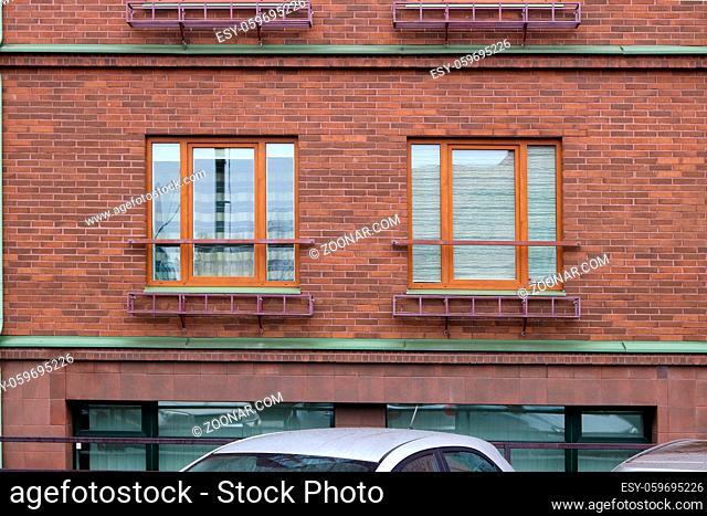 Two modern red plastic windows in a red brick  house wall
