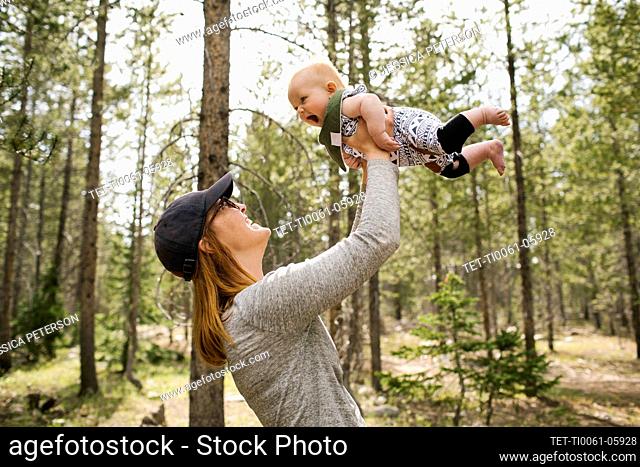 Smiling woman playing with baby son (6-11 months) in forest, Wasatch-Cache National Forest