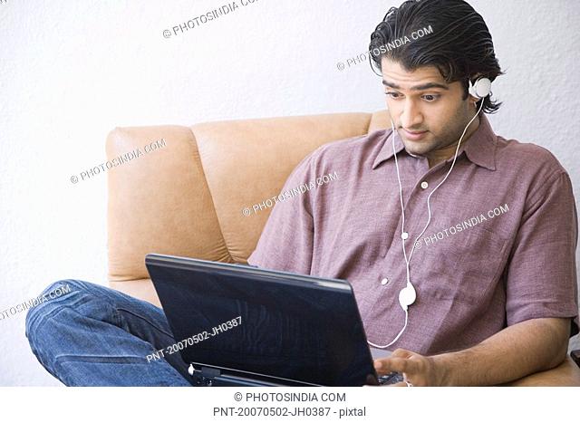Young man sitting in an armchair and using a laptop