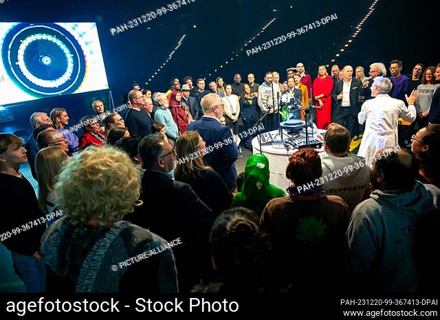 20 December 2023, Hamburg: The participants stand in a circle around the sound and image technology of sound artist Kymat and hum a sound