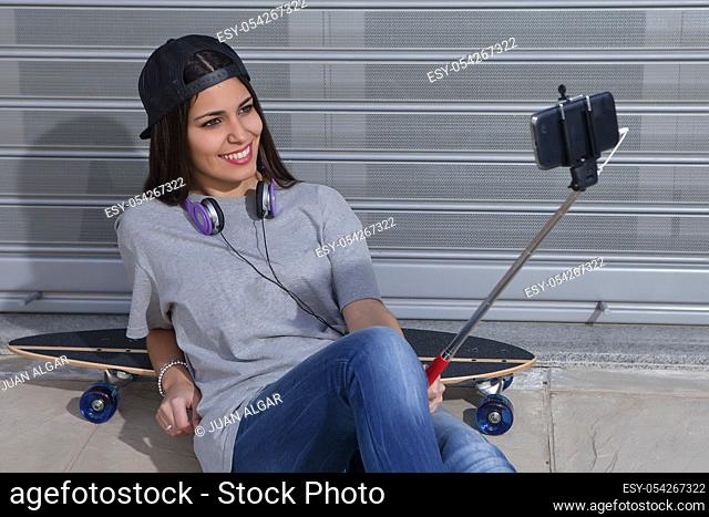 Young female with headphones taking selfie while laying back on skateboard