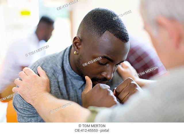 Man comforting young man in group therapy