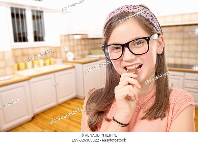 a adorable preteen girl with glasses eats chocolate, kitchen background