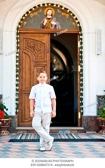 Portrait of little boy on white wear and bow tie on first holy communion background church gate