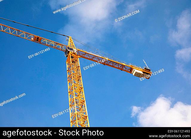 Low angle view of yellow crane tower with blue sky and white clouds background, on building site in Oslo