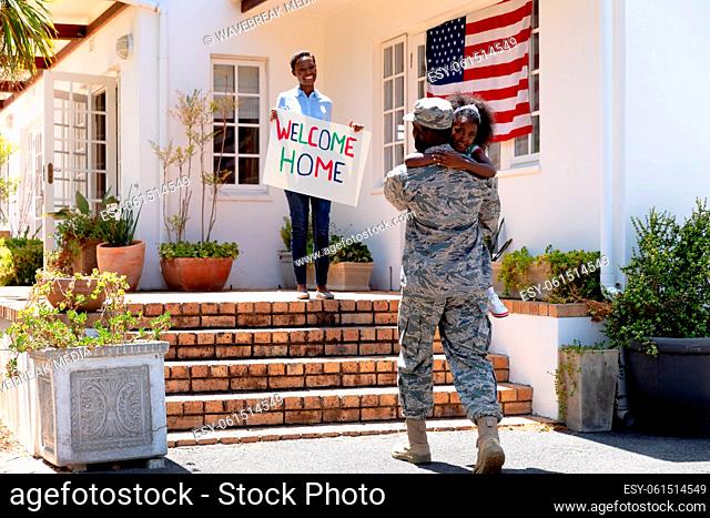 African American woman and her daughter standing welcoming an African American soldier