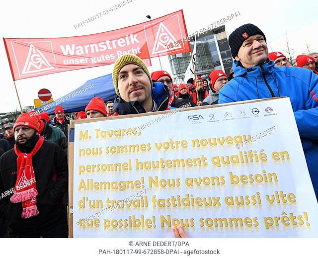 An Opel employee holding a sign with a message in French addressed to PSA CEO Tavares during a rally in front of the Adam Opel House in Ruesselsheim, Germany