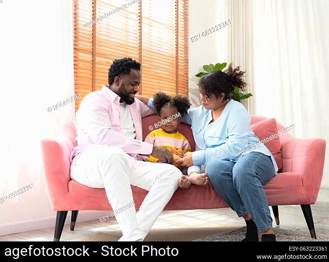 Portrait of happy african family with little curly girl sit relax on pink couch in living room at home