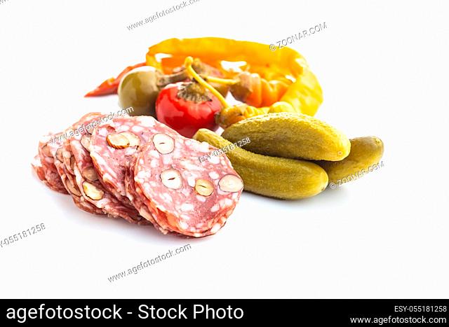 Sliced italian salami with hazelnuts, pickled chili peppers and pickles isolated on white background