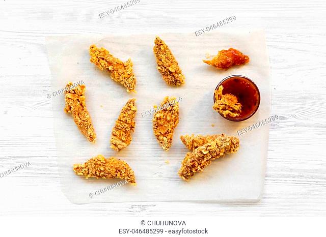 Fried chicken strips with sauce on white wooden table, top view. Flat lay, from above, overhead. Close-up