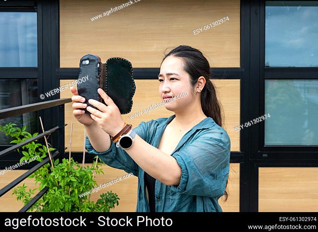 Portrait of a 32 year old Japanese woman, taking a photo with her smartphone, Belgium