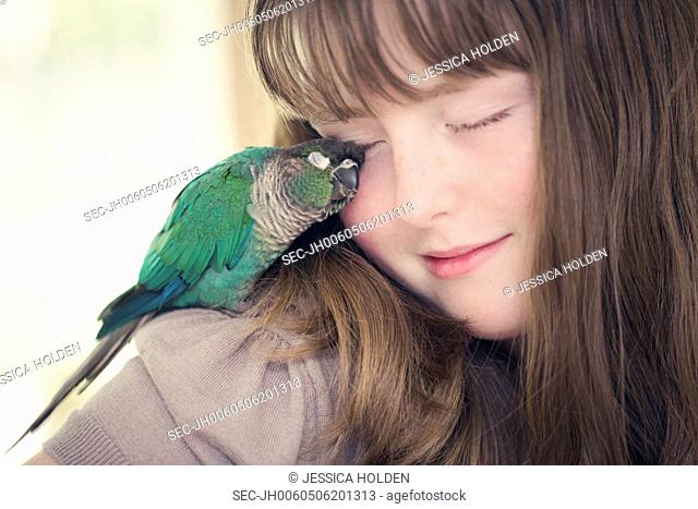 Portrait of girl (13-15) cuddling with parrot