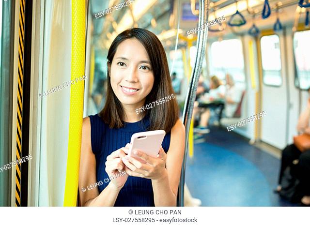 Woman using smart phone inside train compartment