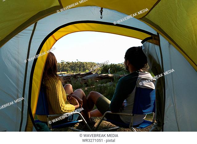 Couple relaxing near tent in the forest