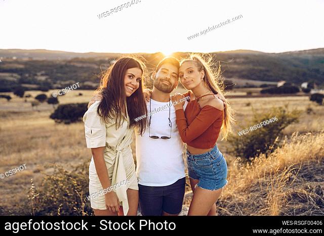 Smiling young man with female friends standing on field