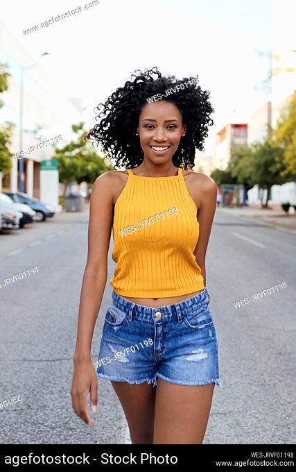 Smiling curly haired woman walking on street