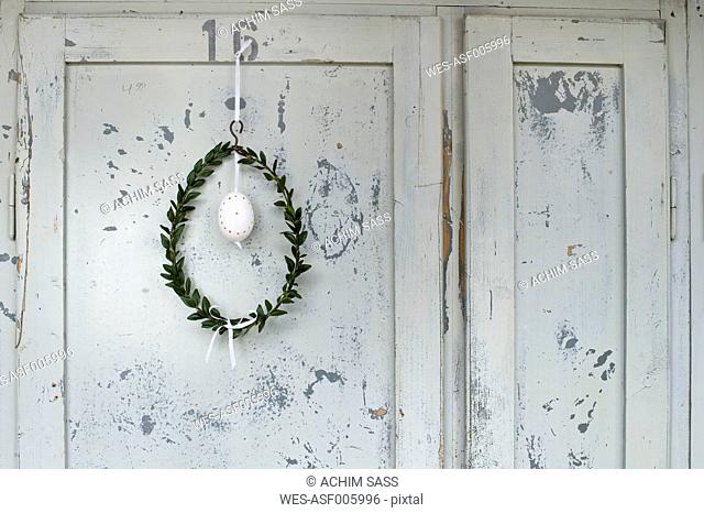 Easter egg and box tree wreath hanging in front of wooden door