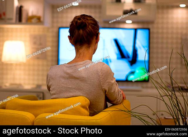 Pretty, young woman watching TV at home (color toned image; shallow DOF)