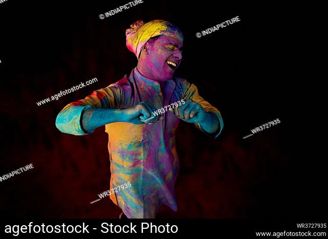 Young man with gulal on his face dancing in amusement on Holi