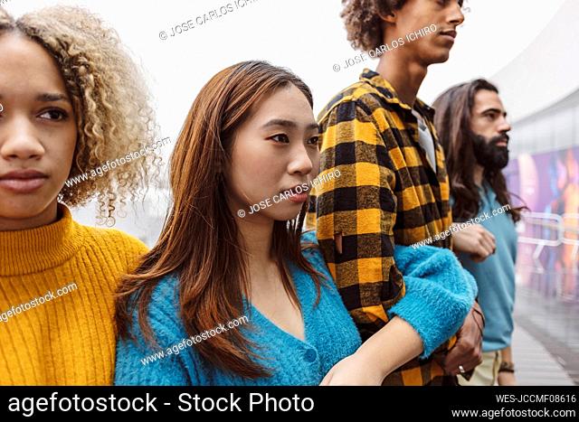Confident young woman in sweater standing with diverse activists