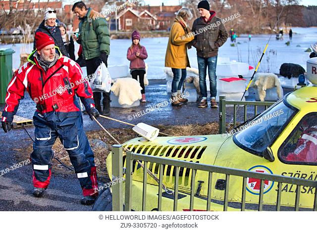 Crew member pulling covered hovercraft of the Swedish Sea Rescue Society off the ice of Lake Malaren, Sigtuna, Sweden, Scandinavia