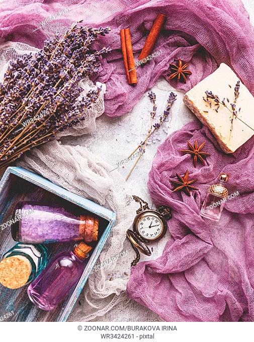 Bottle with aromatic lavender oil and sea salt in a wooden box, a bottle of perfume, a bouquet of lavender, piece of soap and a vintage pocket watch