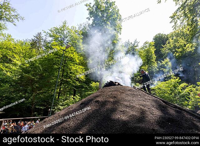 27 May 2023, Saxony, Tharandt: A charcoal pile is fired in the Breiten Grund in the Tharandt forest by members of the Meiler Tharandt e.V