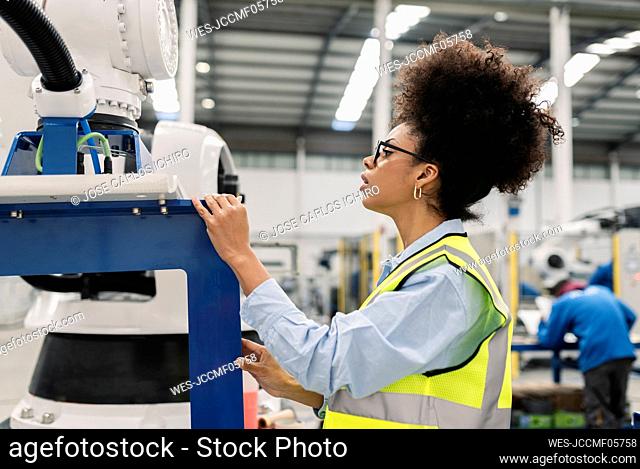 Technician analyzing robotic arm machine in factory
