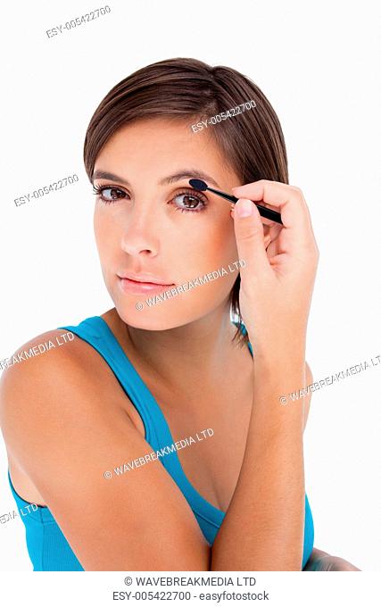 Beautiful teenager putting eyeshadow on her eyelid
