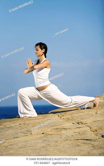 Young woman practicing yoga by the sea
