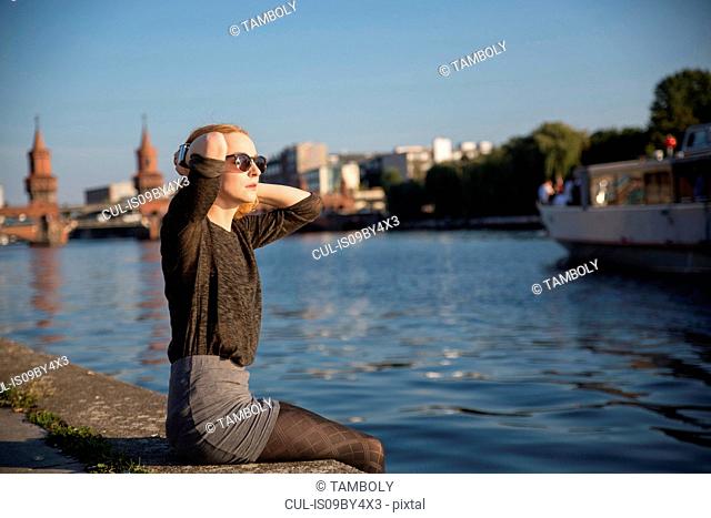 Young woman relaxing by river in summer, Berlin, Germany
