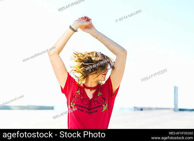 Happy young woman outdoors shaking her hair