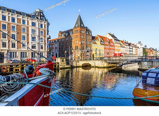 Moored boats and canal bridge with view of Bethel aka Somandshjem hotel and colourful 17th century apartment buildings along the Nyhavn canal, Copenhagen