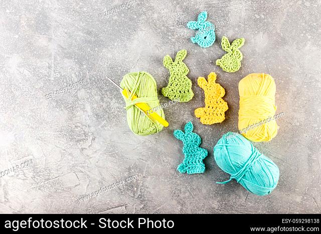 Easter decoration, bunny rabbits made of crochet colorful yarn ongrey texture background. Homemade decor. Top view. Spring Easter holydays concept