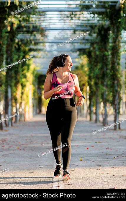 Young female athlete running in public park