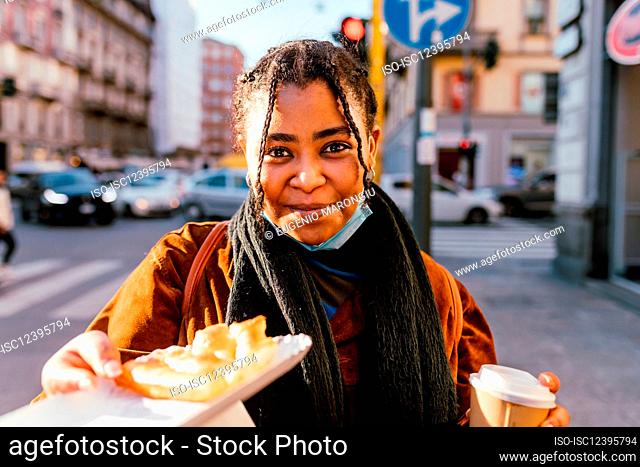 Italy, Portrait of smiling woman with snack on street