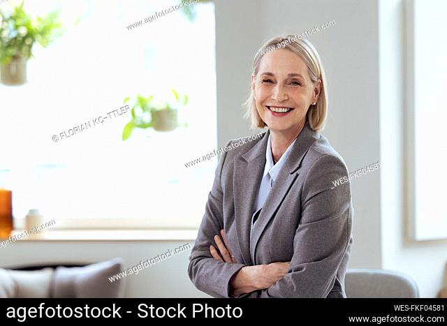 Smiling senior businesswoman with arms crossed in office