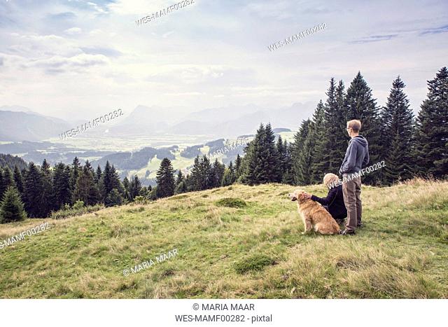 Austria, Tyrol, Kaiser mountains, mother and adult son with dog on a hiking trip in the mountains