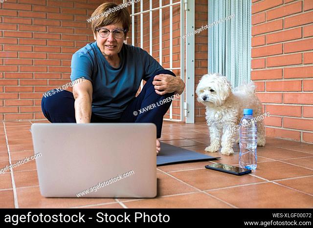 Sportive senior woman using laptop on balcony