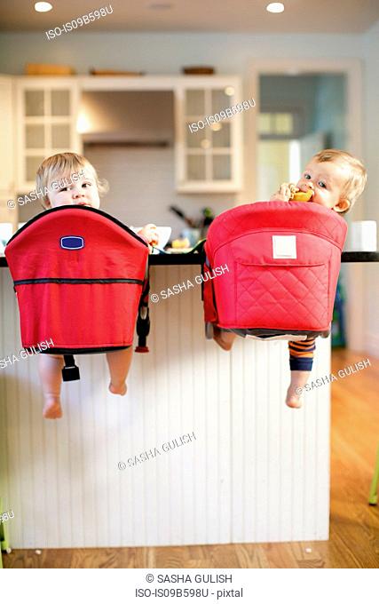 Rear view portrait of male and female toddlers looking back from kitchen counter