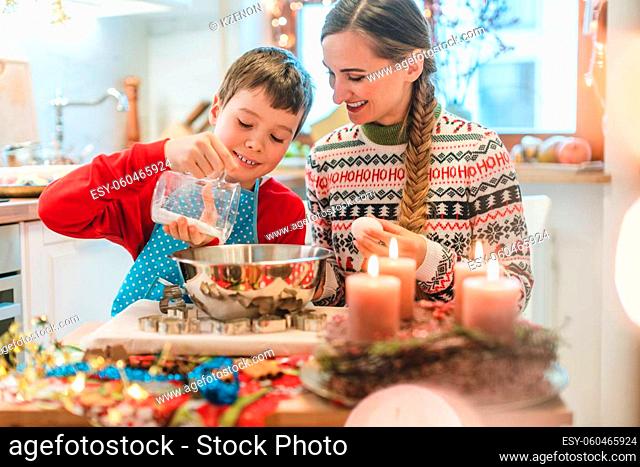 Boy mixing dough for Christmas cookies helping his mother baking in the kitchen