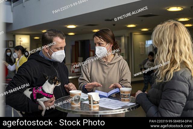 18 March 2022, Berlin: Veterinarian Karin Elisabeth Lason (M) talks to a couple from Ukraine about the necessary vaccinations for their dog Tessa in the main...